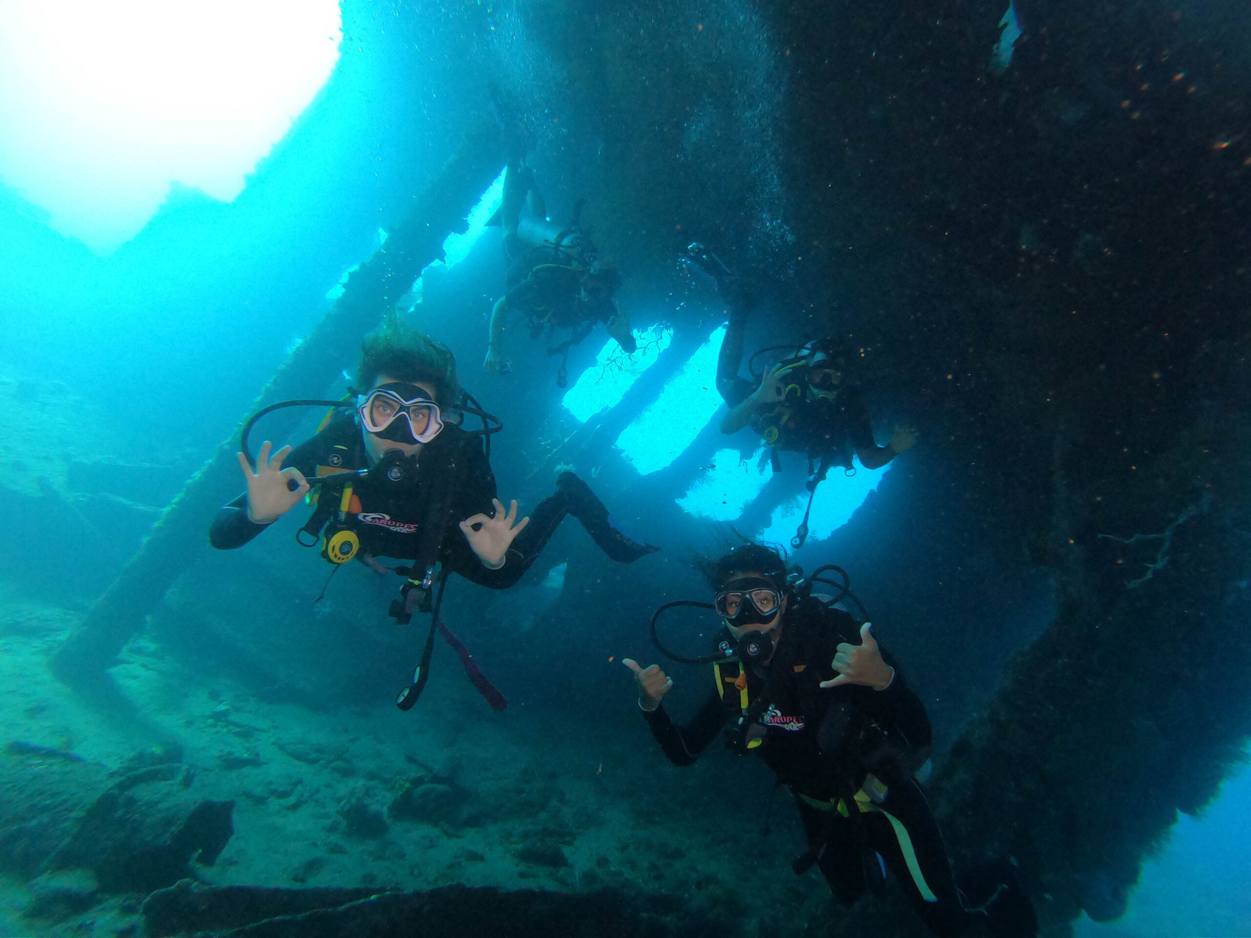 Scuba divers exploring the broken USAT Liberty shipwreck in Tulamben, Bali, surrounded by tropical marine life.