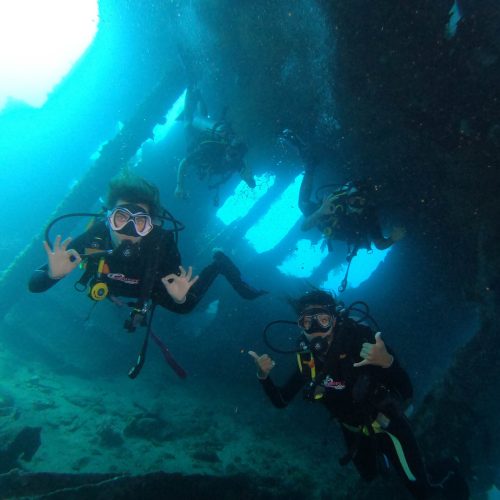 Scuba divers exploring the broken USAT Liberty shipwreck in Tulamben, Bali, surrounded by tropical marine life.