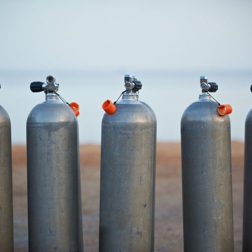 Collection of grey scuba diving air oxygen tanks waiting lined up.